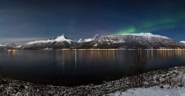 Bright aurora lights dancing across a dark night sky during a solar storm.
