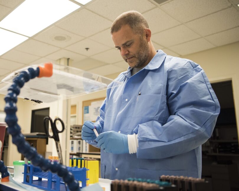 A clinician holding a blood sample vial in a modern laboratory