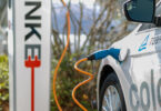 An electric car at a charging station with its battery pack visible