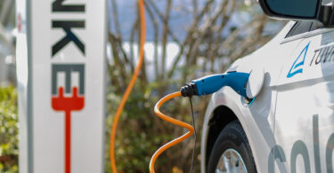 An electric car at a charging station with its battery pack visible
