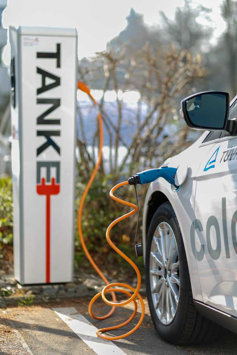 An electric car at a charging station with its battery pack visible